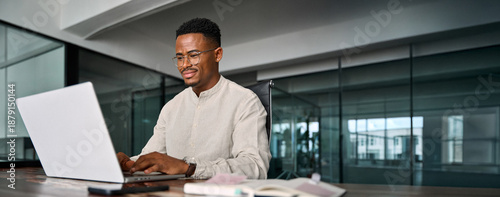 Εκτύπωση καμβά Busy smiling professional African business man company employee, young male worker businessman wearing glasses typing on computer using laptop working at office, elearning at workplace desk