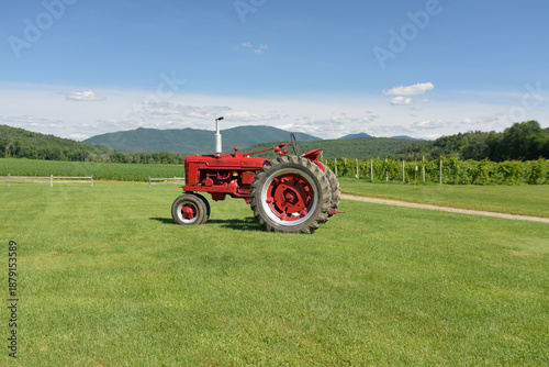 Old Red Tractor in a Green Field with Mountains Behind