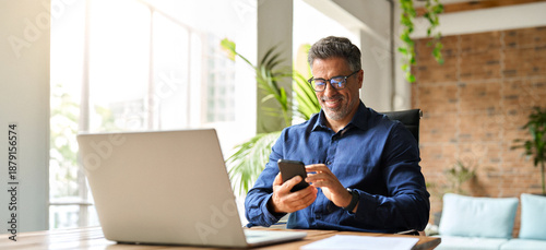 Canvastavla Happy middle aged businessman using mobile phone working in office