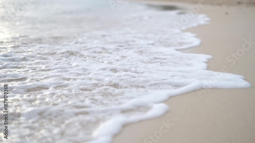 Gentle sea waves rolling onto smooth beach sand creating a peaceful scene
