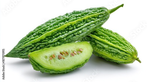 Whole and sliced bitter melon gourd with visible seeds and ridged green skin on white background for Asian cooking 