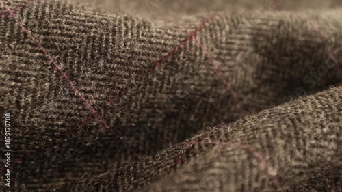 Hands touching soft wool fabric. Dark grey English tweed plaid wool fabric. Appreciating pleasant texture of high quality textile for clothes. Soft and cosy textile. Dark color winter knitted textile.