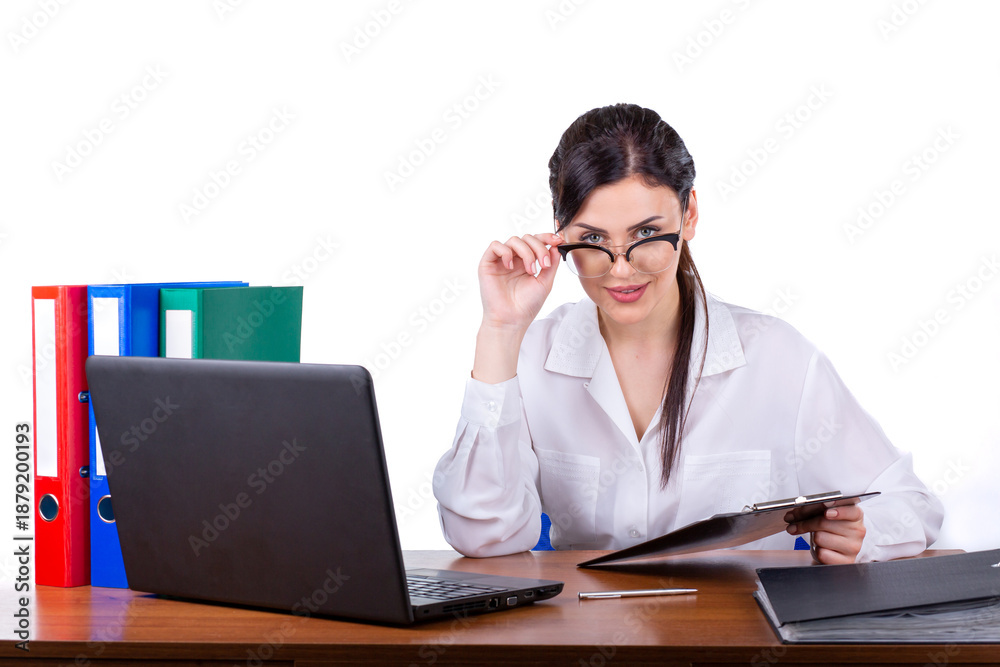 Fototapeta premium Smiling professional businesswoman holding clipboard at office desk with laptop isolated on white background