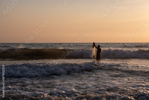 Foto Fisherman throwing a cast net or atarraya at the seashore with water at his waist