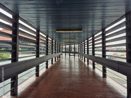 Classic airport terminal connecting corridor with wooden ceiling, ventilated wooden walls, and brown tile floor, designed for natural airflow, comfort, and traditional architectural style.