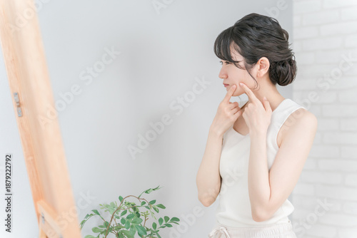 Photos Asian woman looking in the mirror suffering from acne, rough skin and pimples