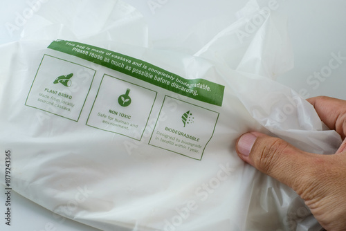Hand holding eco friendly biodegradable plastic bag with sustainability labels. Perfect for sustainability campaigns, eco education, green business content, waste reduction, and green lifestyle