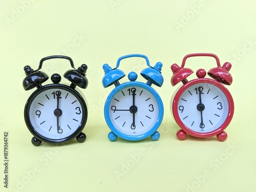 Bild auf Leinwand Three colorful analog alarm clocks set to 6:00, showcasing classic design and sy
