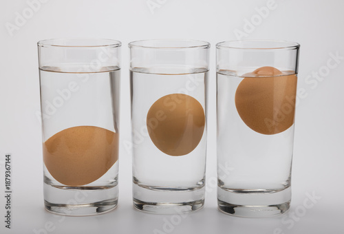 Eggs in water test on transparent glass , Egg freshness test on white background , Bad egg floats in water