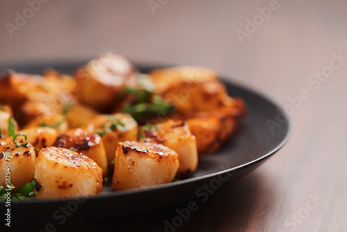 Obraz na płótnie Seared scallops on black plate closeup