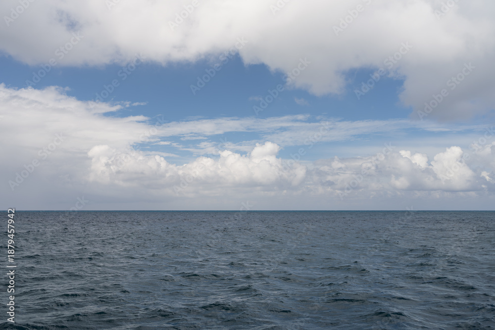 Obraz premium Ocean waves with turquoise water and white clouds