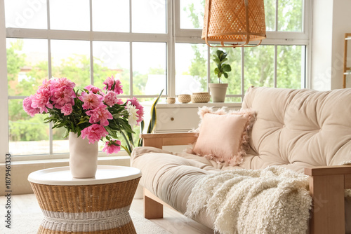 Cozy sofa and coffee table with peonies in interior of living room