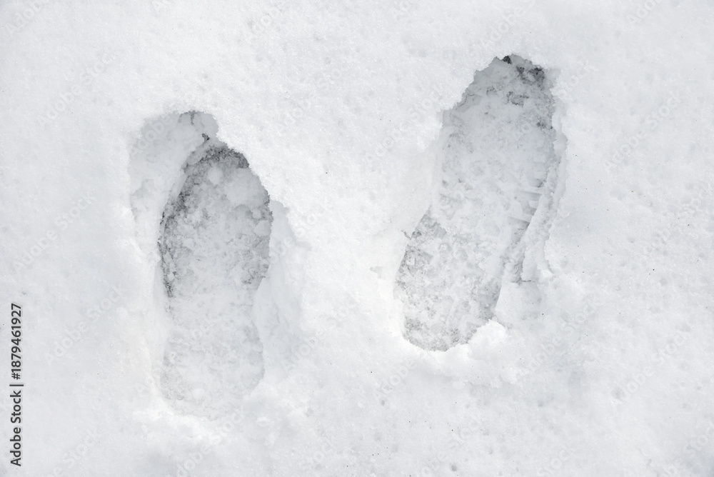 Fototapeta premium Pair of boots or shoes track in the snow. Pair of footprints in the snow. Texture of snow surface. Top view. Close-up. 