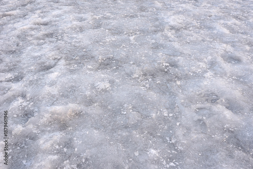 Sidewalk covered with ice in winter. Slippery ice on the sidewalk in winter. Frozen sidewalk dangerous for walking. Close-up. Selective focus.