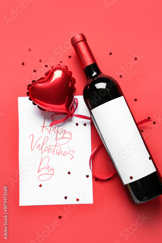 Bottle of wine with postcard, balloon and confetti on red background. Valentine's Day celebration