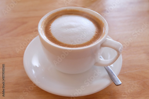 Cappuccino coffee in white cup on wooden table, stock photo