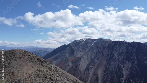 A girl walks along a mountain range. There are snowy mountains in the background. Active recreation
