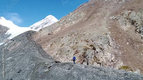 A girl walks along a mountain range. There are snowy mountains in the background. Active recreation