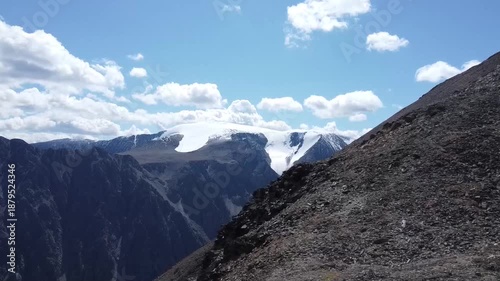 A girl walks along a mountain range. There are snowy mountains in the background. Active recreation