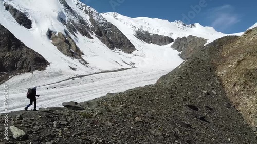 A girl walks along a mountain range. There are snowy mountains in the background. Active recreation