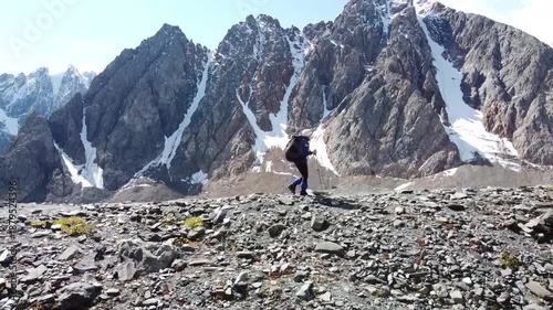 A girl walks along a mountain range. There are snowy mountains in the background. Active recreation