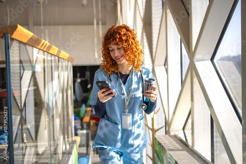 Mid adult female nurse taking a break in the hospital cafeteria, using a phone while enjoying a moment of relaxation