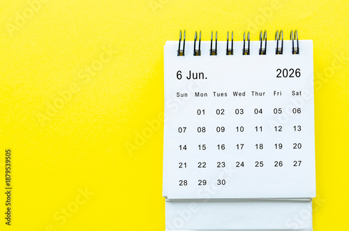 Top view of June 2026 table calendar with space for text on yellow background.