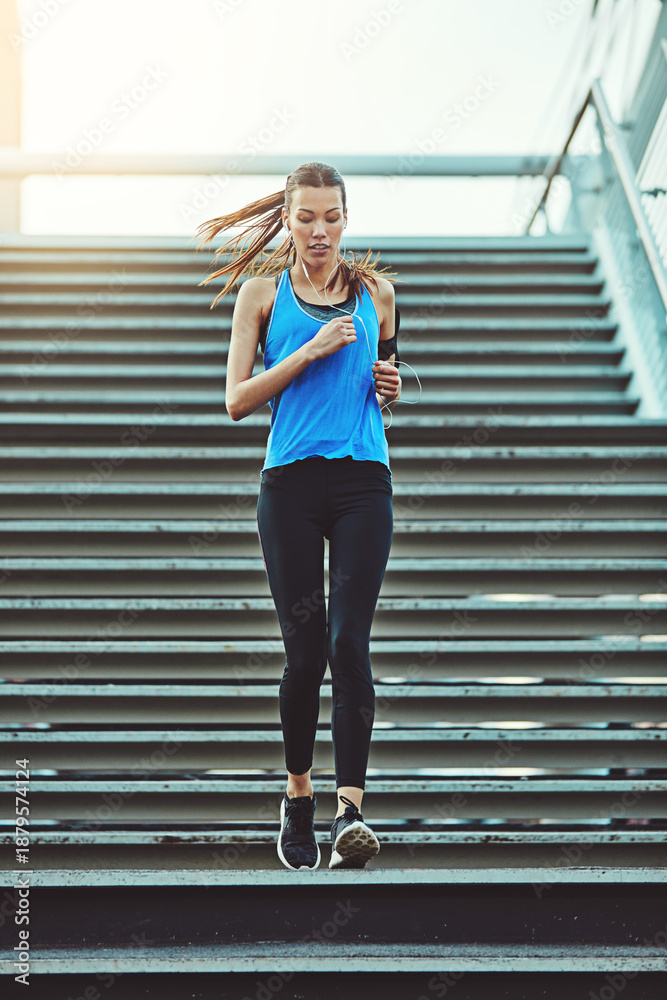 Obraz premium Running, music and stairs with woman in city for health, workout playlist and cardio challenge. Wellness, exercise podcast and low angle with person and earphones for runner training and endurance