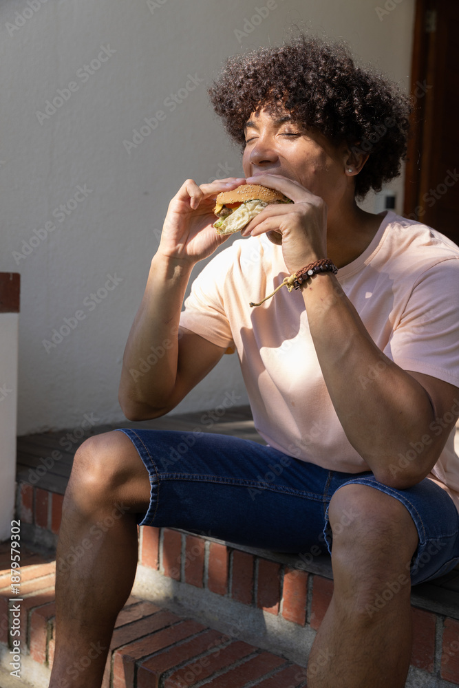 Fototapeta premium Burger being bitten on sunlit brick steps at front porch