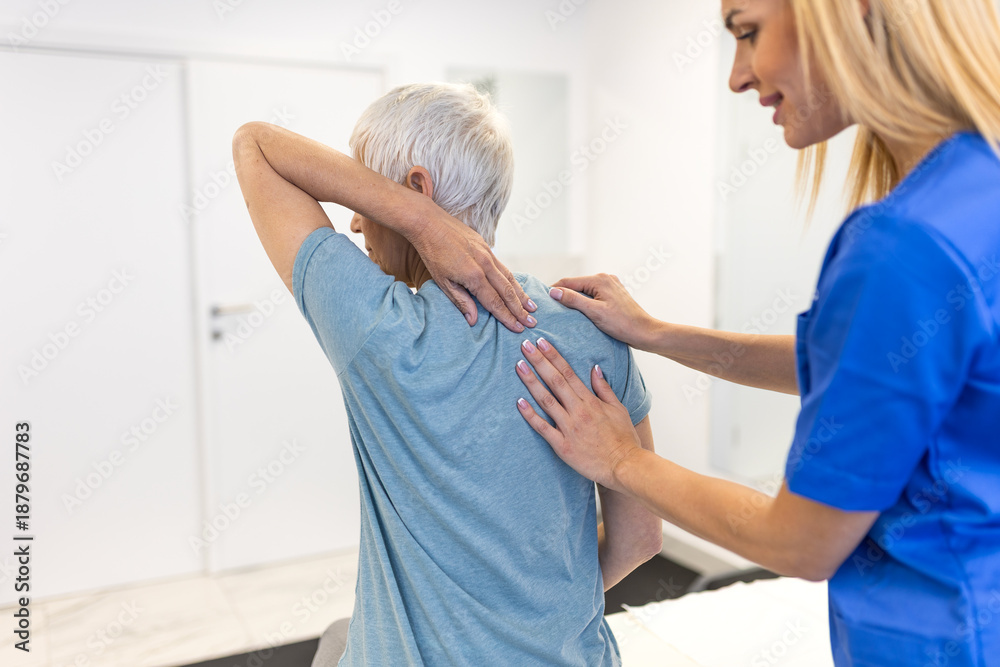 Obraz premium Female physical therapist in blue uniform guiding a senior woman through shoulder and upper back stretches during a rehabilitation session in a modern clinic to treat muscle tension and stiffness.