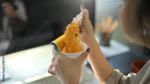 Photography Closeup young woman eating instant noodles in office workplace