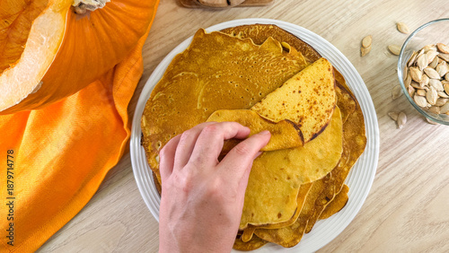 Canvas Print Hand reaching for golden pumpkin pancakes, enveloped by autumn hues, conjuring w
