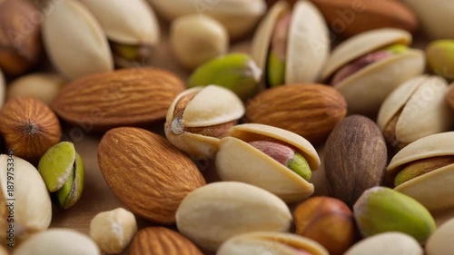 A close up, macro view showcases a textured assortment of healthy raw nuts including vibrant green pistachios alongside rich brown almonds creating a nutritious snack background for dietary needs.