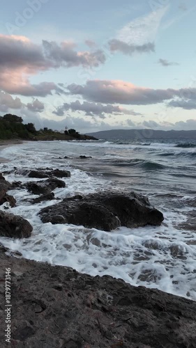 A lighthouse surrounded by rocks in a windy and choppy Aegean Sea. Akyarlar, Bodrum. Vertical video for social media. 