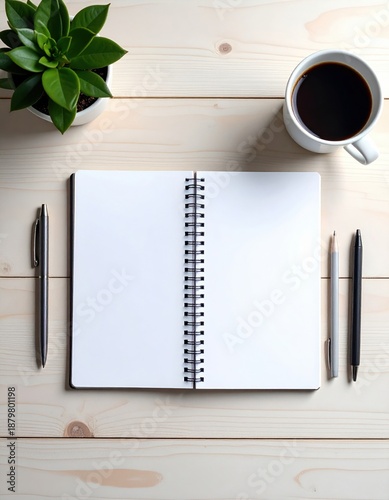 Open blank notebook on light wooden desk with coffee cup and pens, top viewed