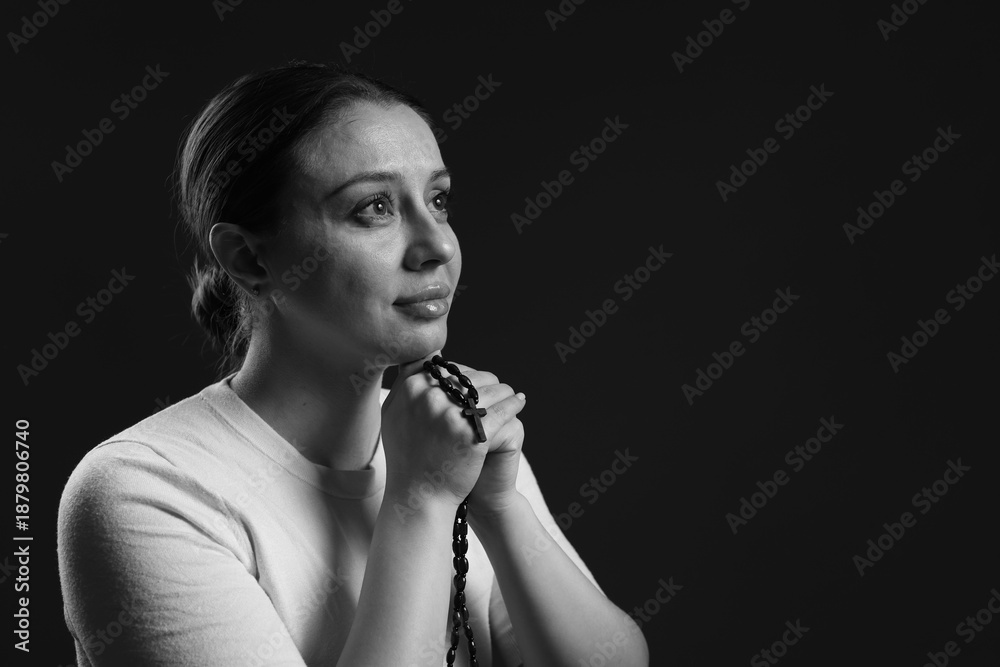 Obraz premium Woman with cross praying on dark background, space for text. Black and white effect