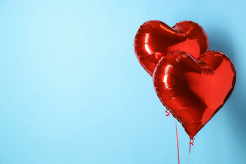 Heart-shaped red balloons on light blue background, space for text. Valentine's Day