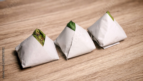 Konstfotografi Traditional packs of nasi lemak wrapped in banana leaf and paper on wooden table