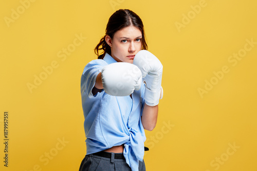 Photos Young woman in boxing gloves posing, showing power and confidence on a yellow ba