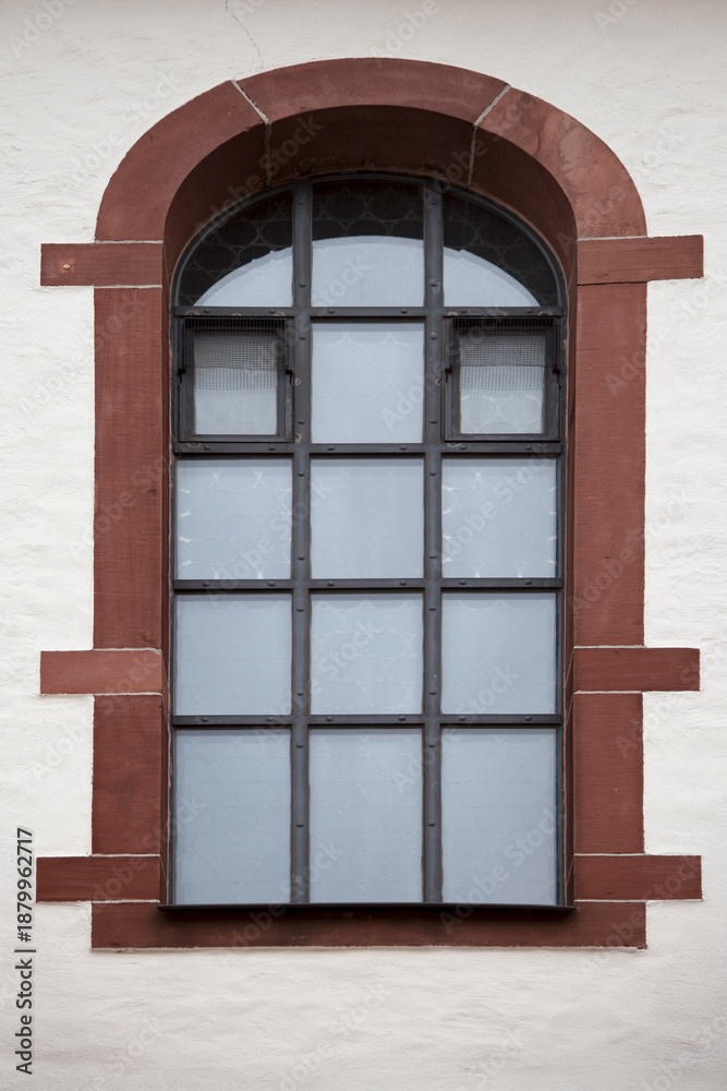 Fototapeta premium Arched window with metal grid in historic wall 