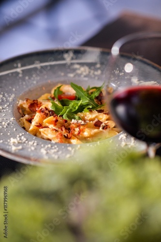 Creamy gourmet pasta with crispy bacon and fresh arugula served in fine dining restaurant with elegant presentation and shallow depth of field