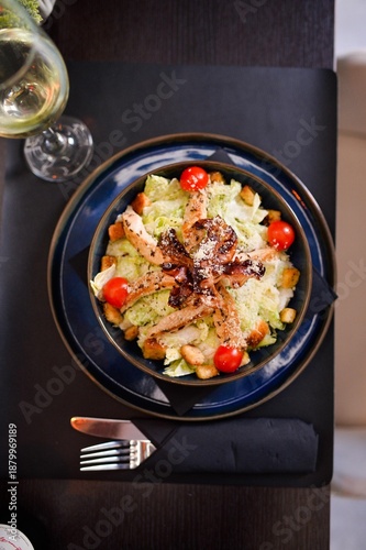Top view of fresh chicken caesar salad with grilled chicken, crispy bacon, croutons and cherry tomatoes served in modern restaurant