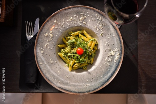 Top view of pesto pasta with penne, fresh arugula and cherry tomato served in elegant bowl at fine dining restaurant