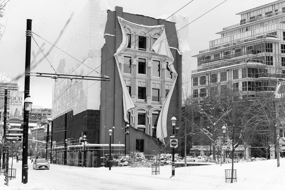 Fototapeta premium black and white view of Flatiron Mural by Derek Besant located at 50 Park Path, west facing wall of Gooderham Building, after a winter storm in Toronto