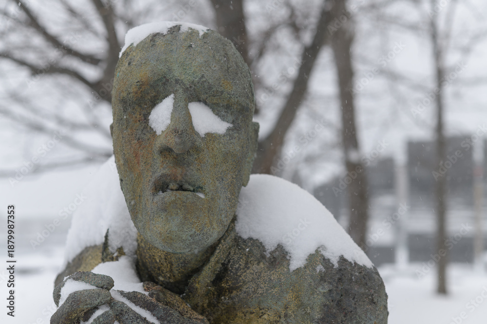 Fototapeta premium front detail of Apprehensive Man created by Irish artist Rowan Gillespie part of The Arrival, set beside the old Canada Malting silos on Eireann Quay, Toronto, during winter storm on 2026-01-15