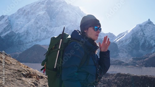 A female trekker pauses to catch her breath on a high-altitude mountain trail in the Himalayas

