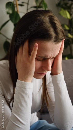 Tired young woman unwell stress headache suffer depression sitting on sofa at home. Sad female head pain ache discomfort migraine overworked exhausted frustrated loneliness anxiety worried problem