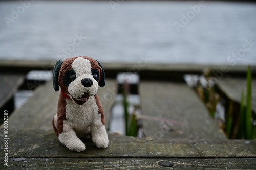A dog is alone on a pier near the lake water.
