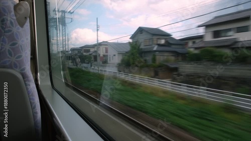 Japanese landscape with traditional houses and rice fields passing by from a high speed train window