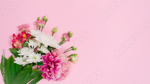 Bouquet of natural white, pink and red flowers appears on a pink background